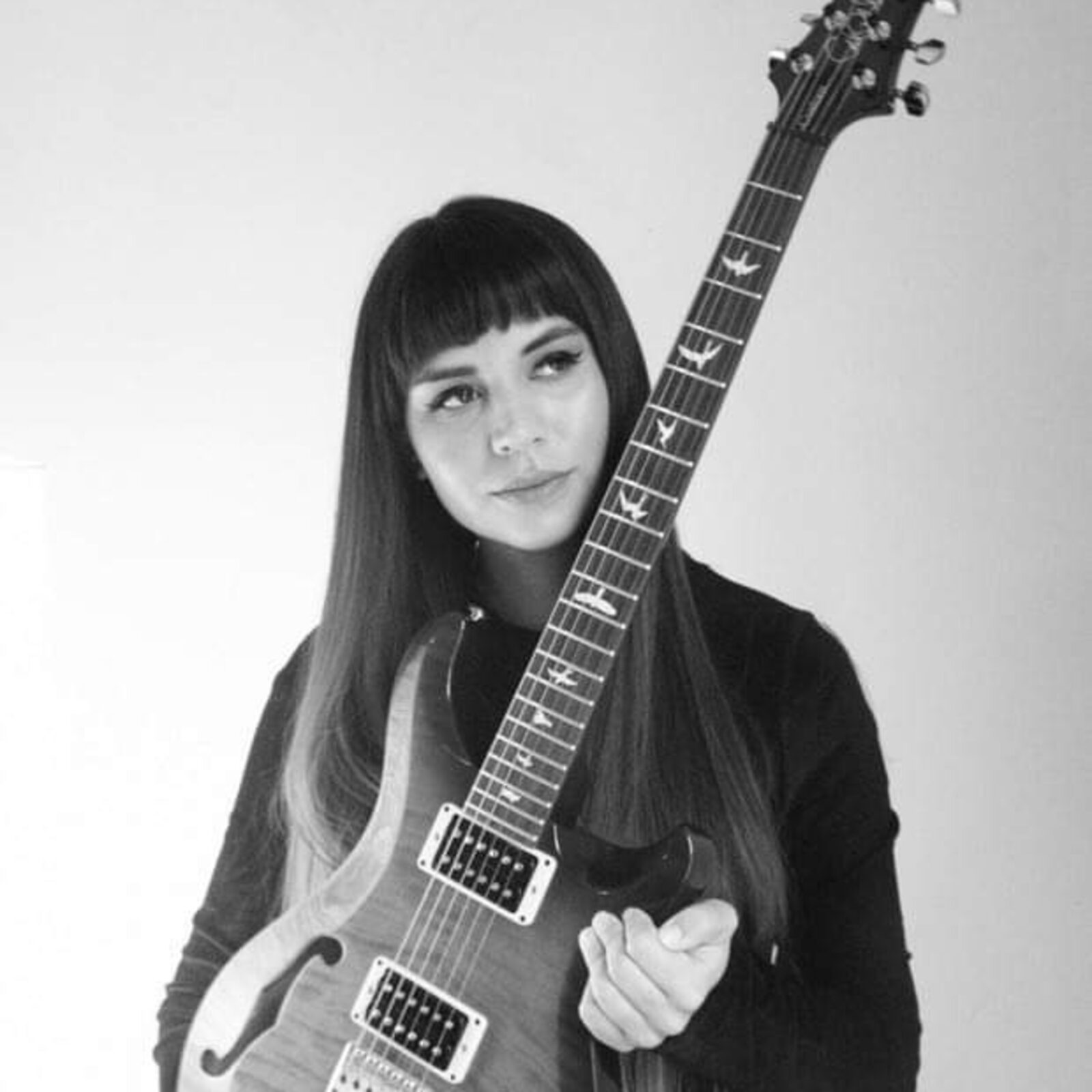 Headshot of Alicyn Yaffee holding her base guitar