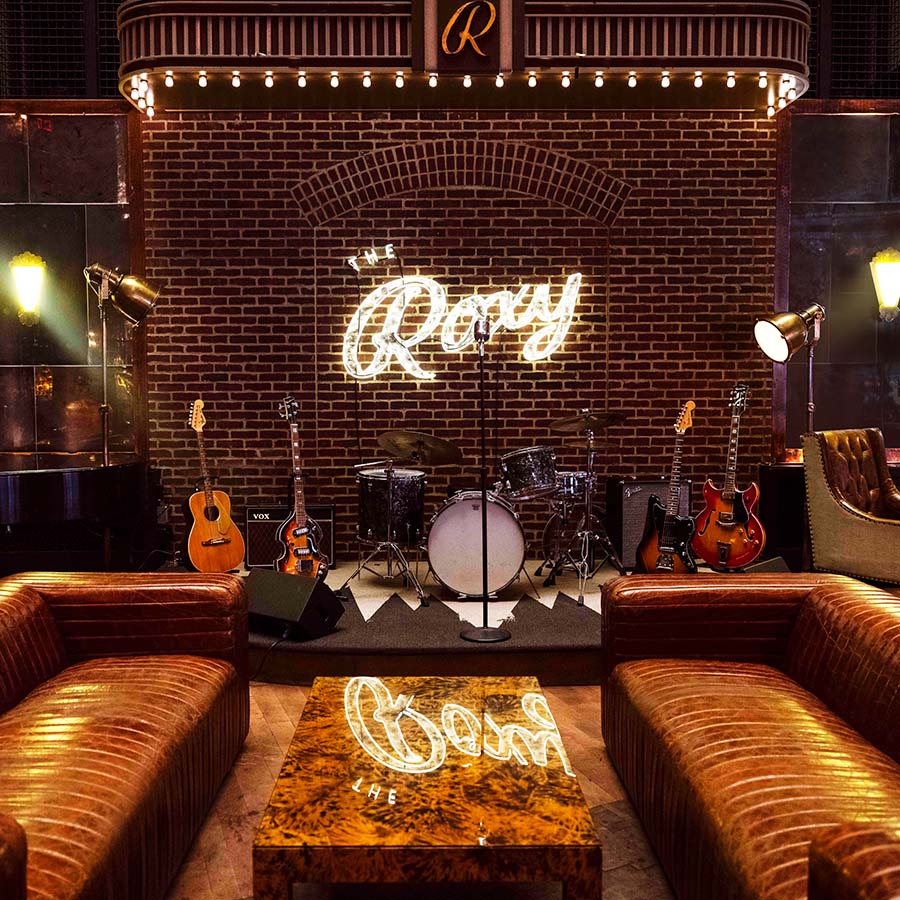 View of the Roxy Hotel stage area with band instruments and two leather couches across from each other in front of the stage