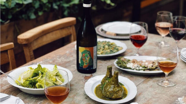 An image of different courses, glasses of wine and a bottle on a table