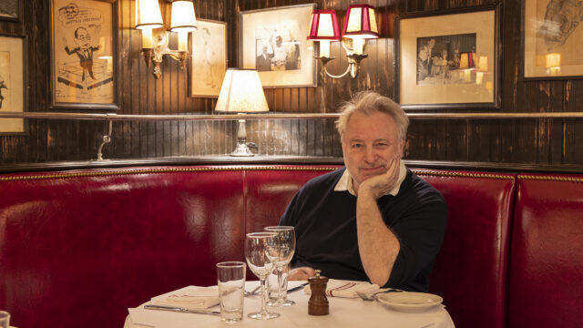 A portrait of restauranteur Keith McNally sitting in a red booth