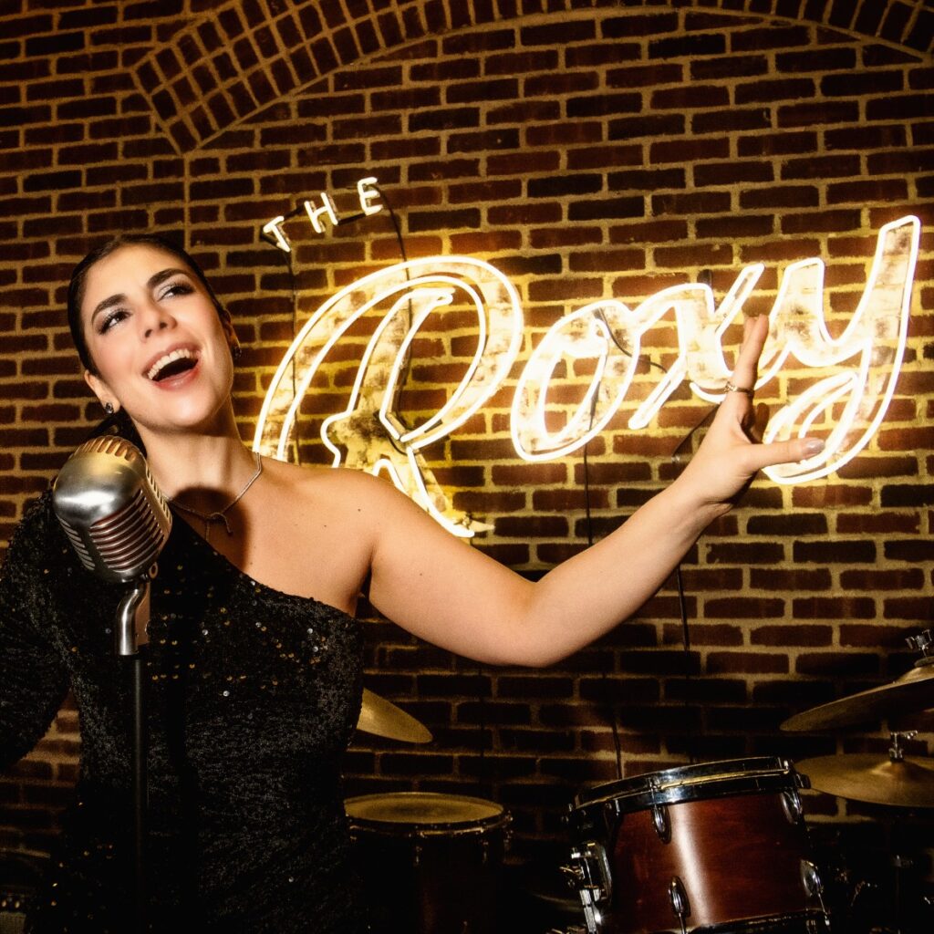 Singer Simona Daniele wearing a black sequins dress singing on the Roxy Bar stage.