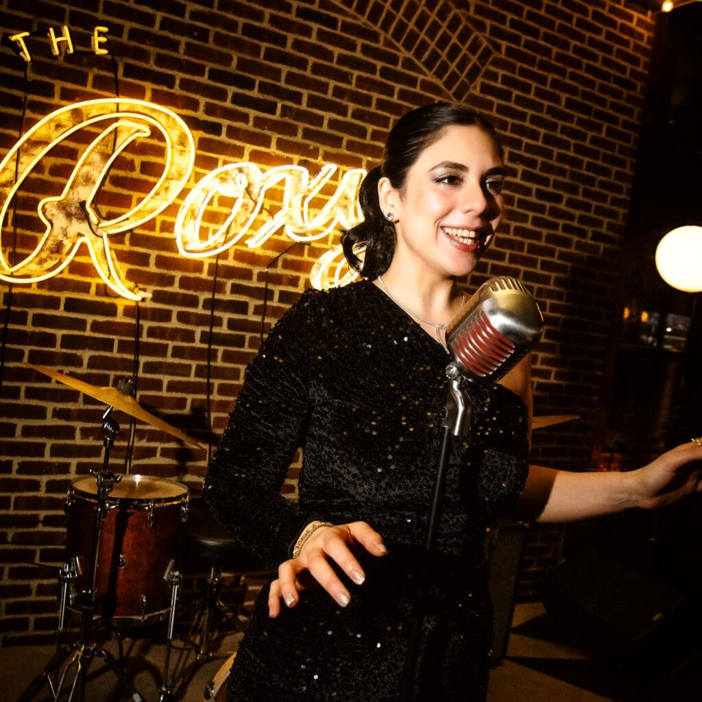 Singer Simona Daniele in black dress singing onstage at Roxy Bar.