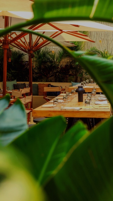 Tables set for dinner as seen through lush greenery at Gilligan's outdoor bar and restaurant in SoHo, NY.