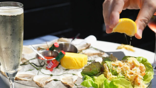 Man squeezing a lemon onto iced seafood dishes at Roxy Café in Tribeca.