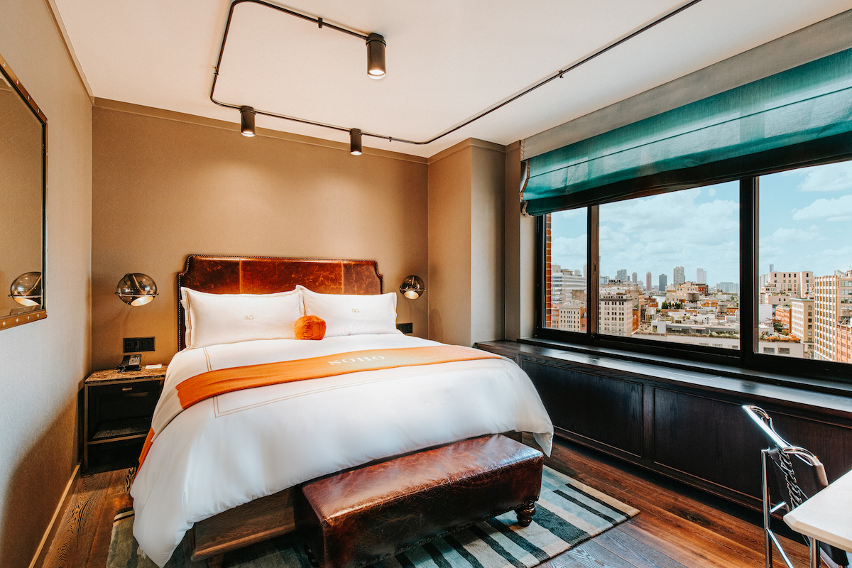 studio king bedroom with a king bed with an orange throw blanker and view of the manhattan skyline