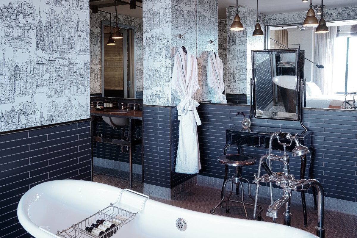 The Loft North bathroom with luxe printed wallpaper, large free-standing tub, walk in shower and a hanging white robe