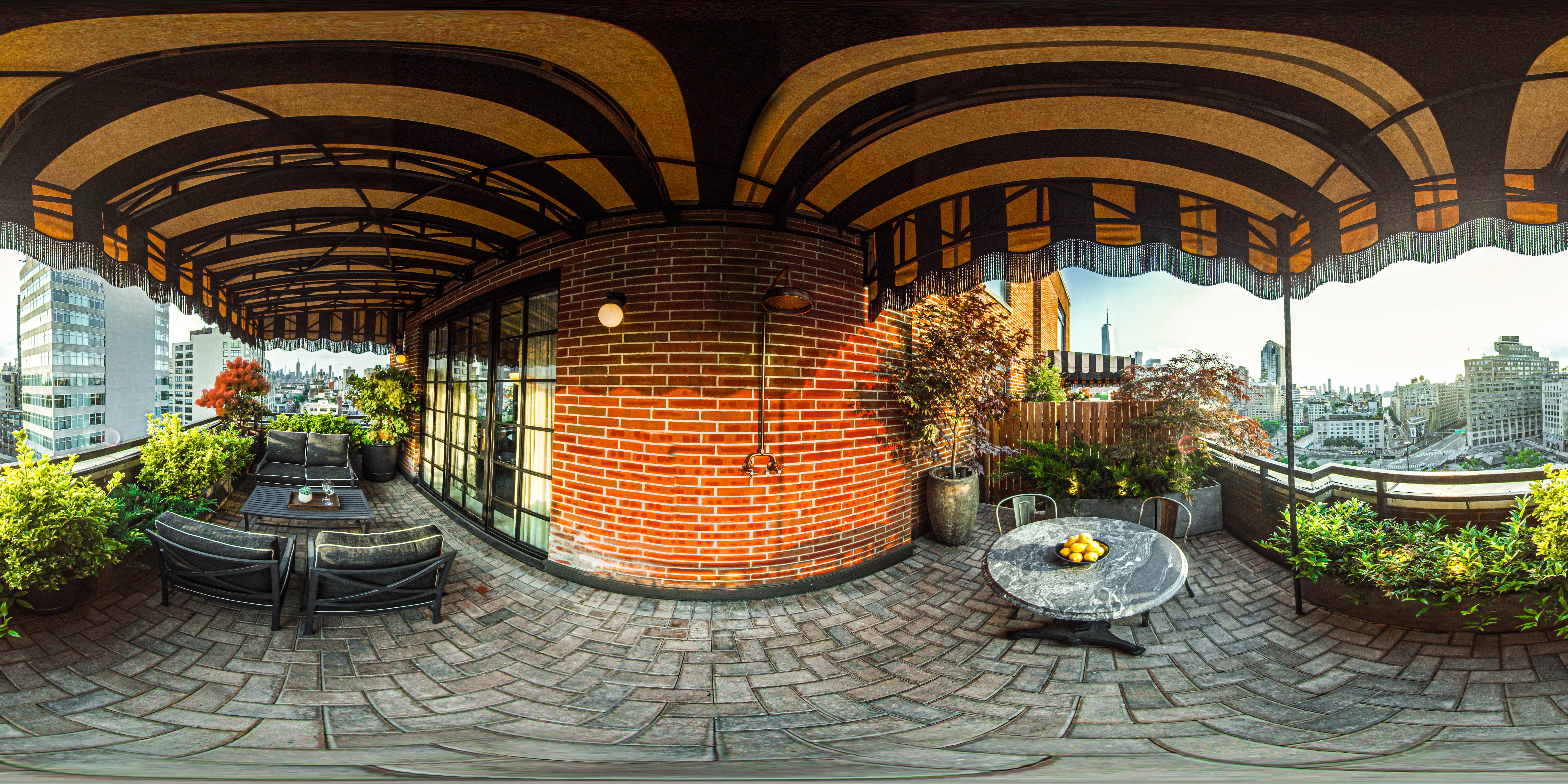 A rooftop terrace with a brick wall, outdoor seating, and a city view.
