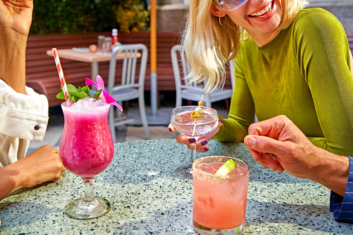 Three patrons enjoying colorful cocktails outdoors in Soho Diner's outdoor garden.
