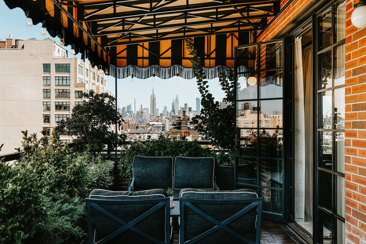 the outdoor terrace of the suite. there are blue velvet couches and a striped awning. there is a great view of midtown manhattan