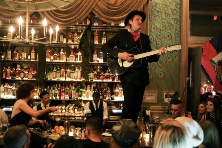 a man stands on top of a bar and plays the guitar at Soho Grand's Club Room