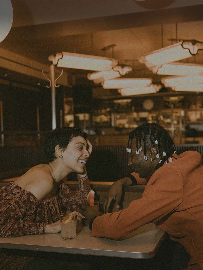 a couple sits at a booth in the soho diner drinking cocktails