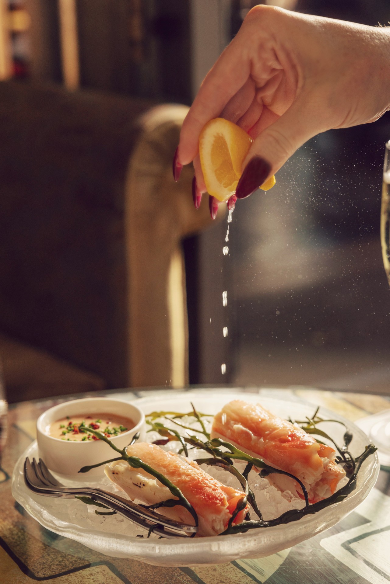 Woman squeezing lemon on top of King Crab Leg at Soho Grand Hotel.