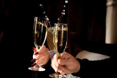 Two full champagne flutes being held up and toasted.