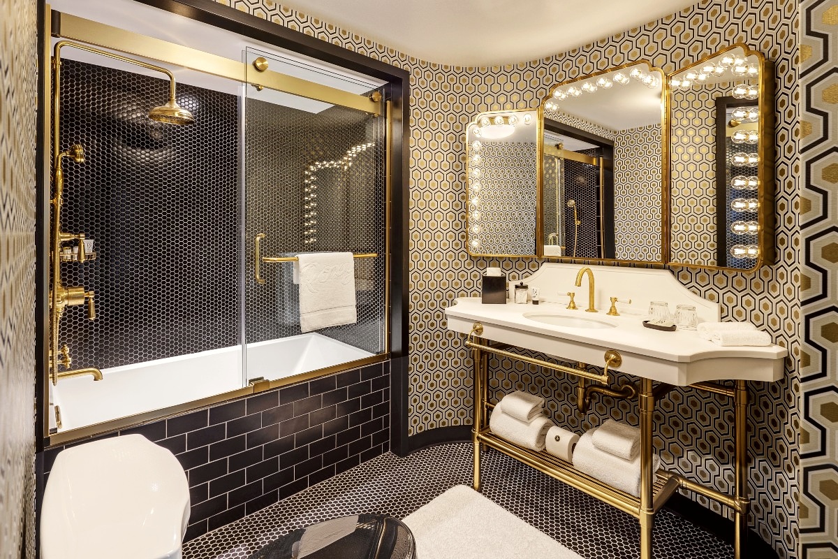 Bathroom vanity mirror, white sink, and black-tiled shower.