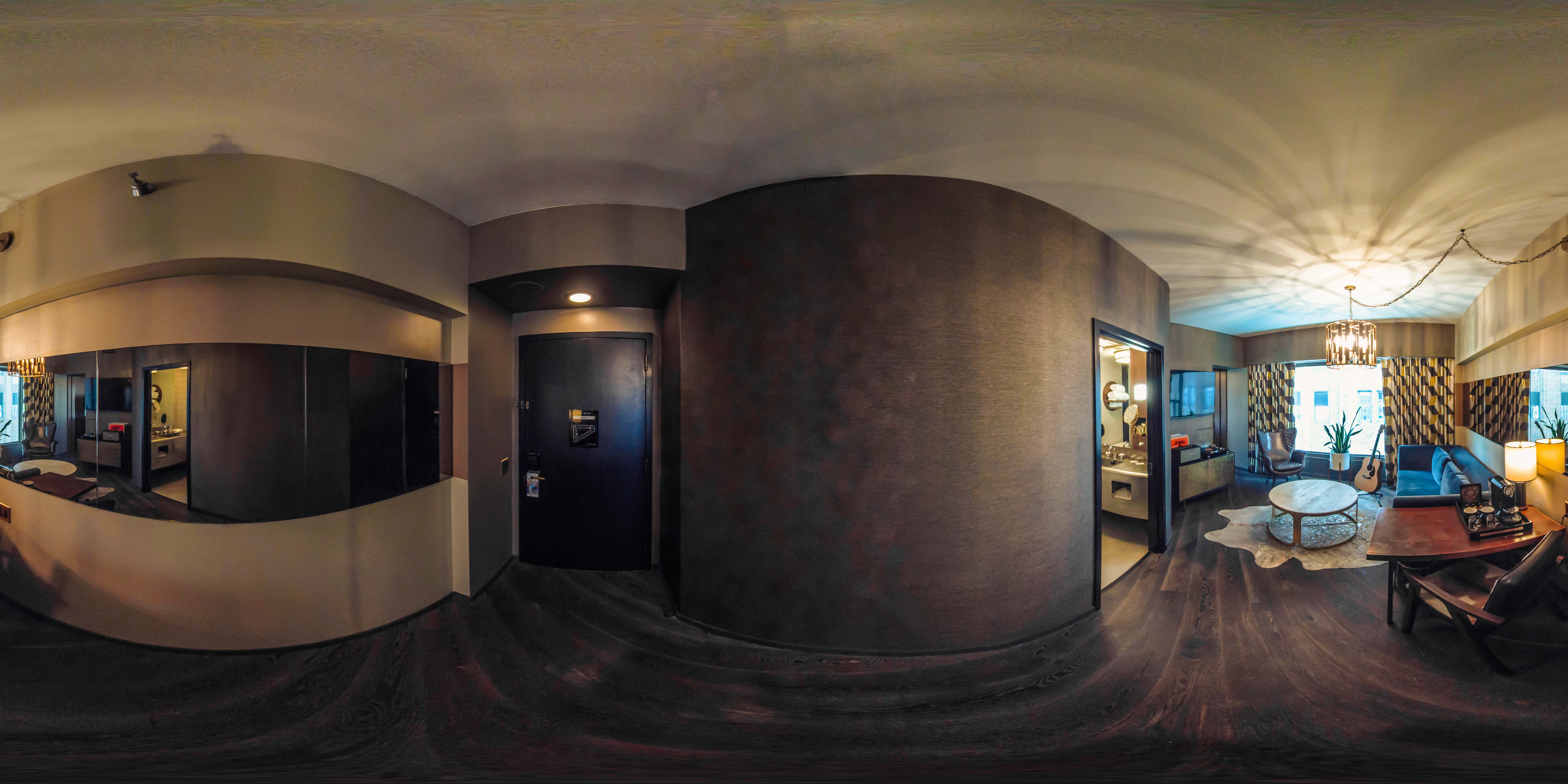 A wide-angle view of a luxurious hotel suite with a living area and a bedroom
