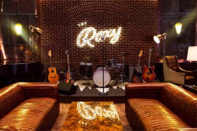 The Roxy Bar stage with guitars and a drum set sitting on stage