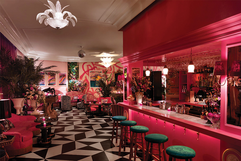 a colorful cocktail lounge with a hot pink bar and black and white patterned accents