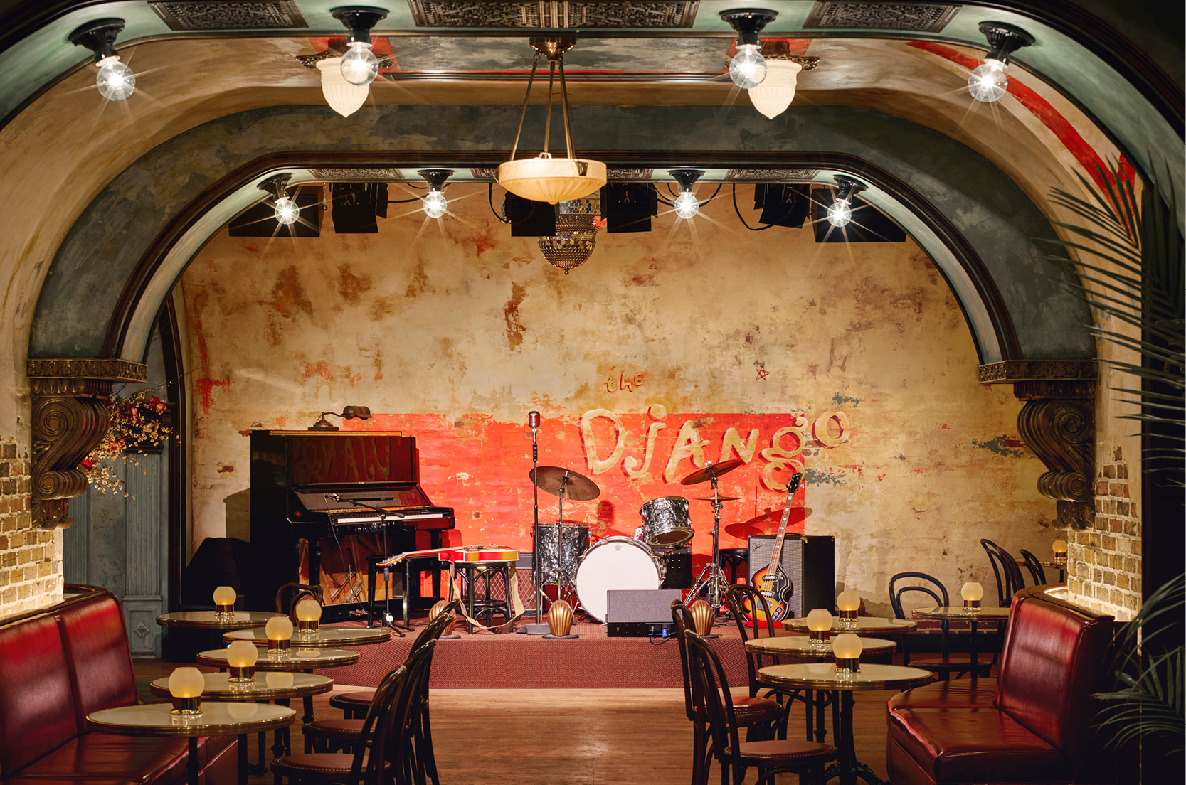 The Django stage with all its instruments including a piano, a drum set and a guitar. There are candlelit tables lining the room