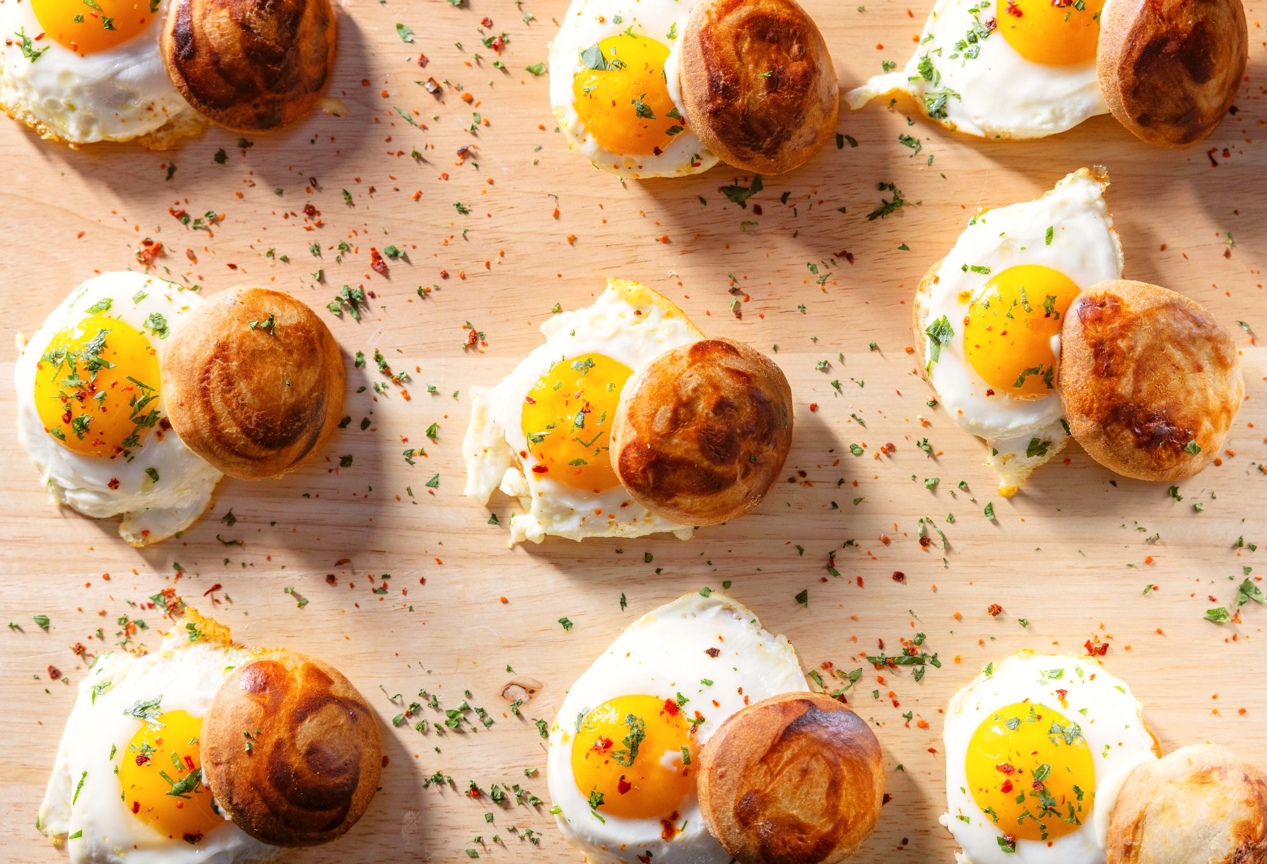 Mini egg sandwiches on a wood tray.