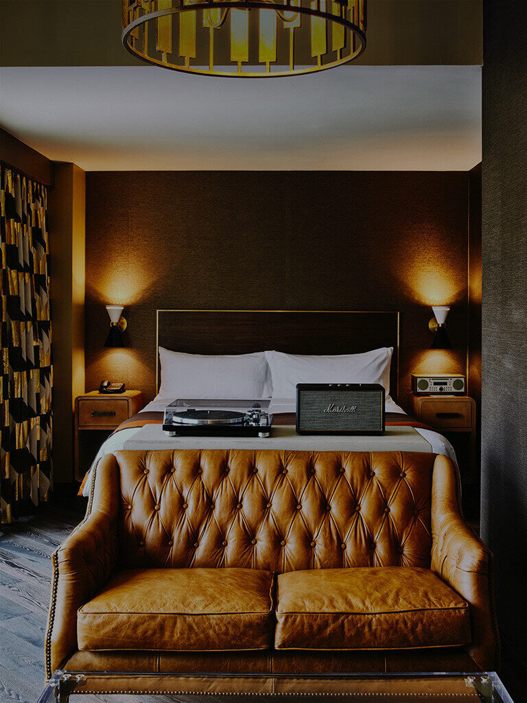 the roxy hotels loft suite bedroom with a bed, love seat and marshal brand turntable and speaker system