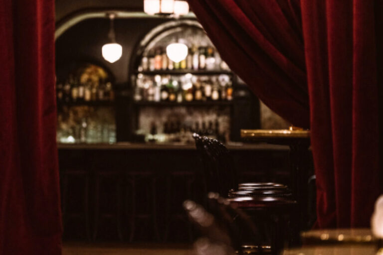 a red curtain is pulled back to reveal the Django Jazz Club bar