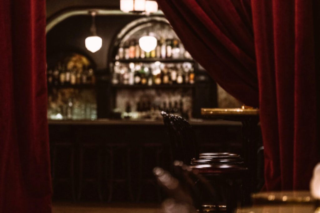 A red curtain is pulled back to reveal the Django Jazz Club bar.