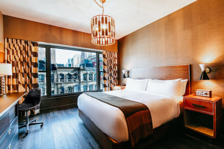The Roxy Deluxe King Room with a bed, bedside table, desk and eccentric interior design details with a view over Tribeca