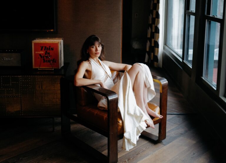 Woman in white dress sitting on chair.