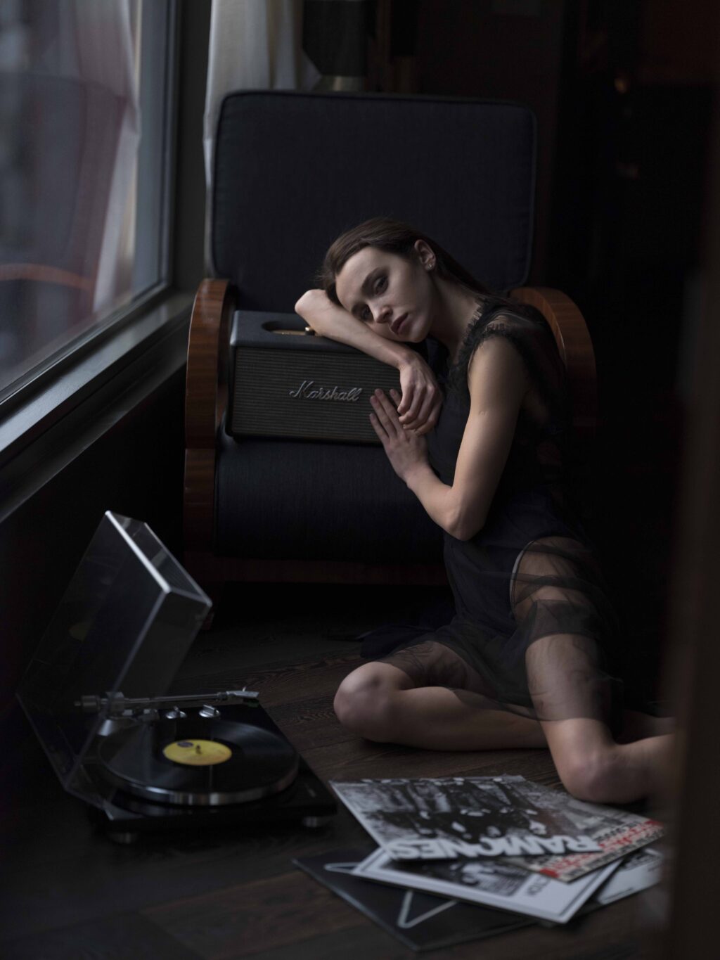 Woman sitting on the floor with vinyl records and leaning on a Marshall speaker.