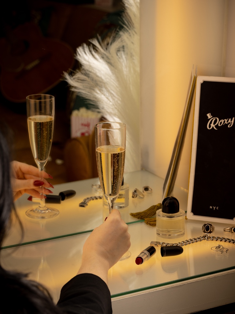 Woman's hand holding a glass of champagne in front of a mirror.