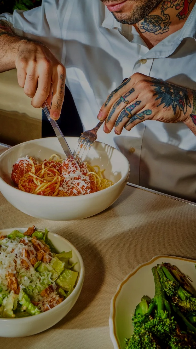 Man with tattoos eating spaghetti and meatballs at Soho Diner.