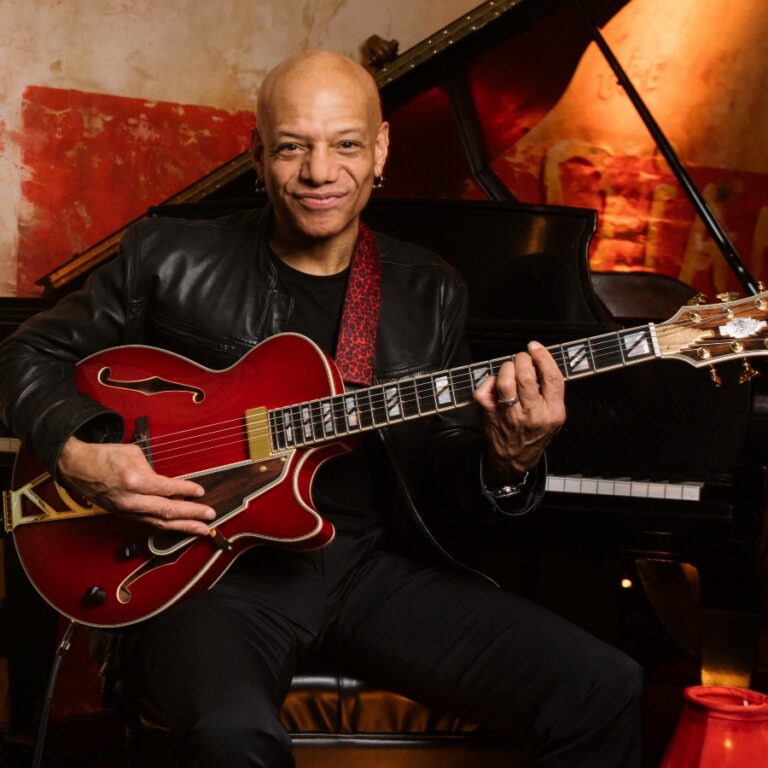 Musician Mark Whitfield holding a guitar on The Django stage.