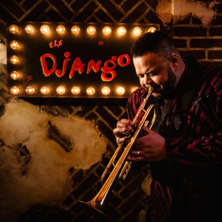 Jumaane Smith with Trumpet at The Django entrance.