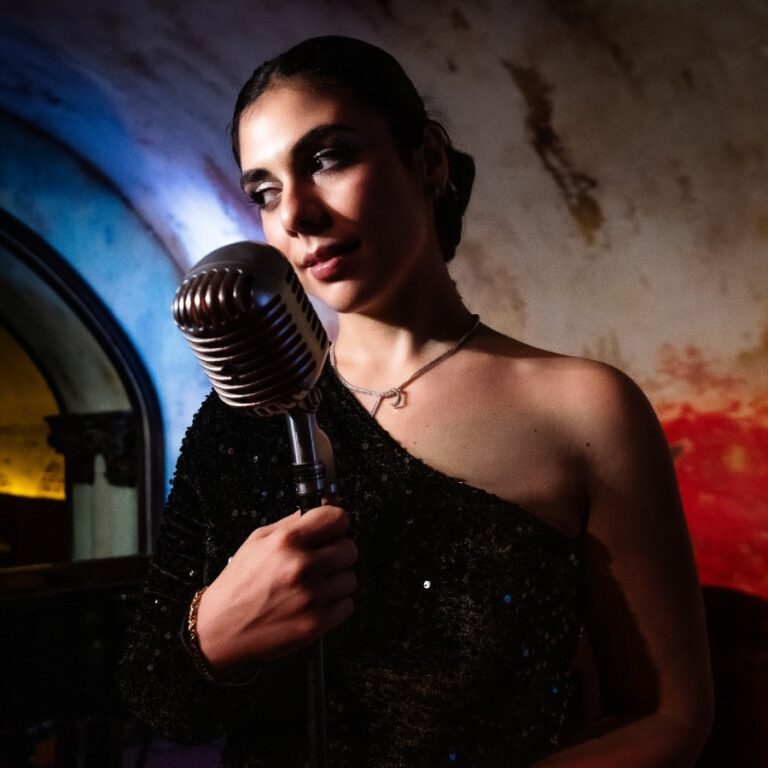 Italian signer Simona Daniele singing into a vintage microphone on stage at The Django.