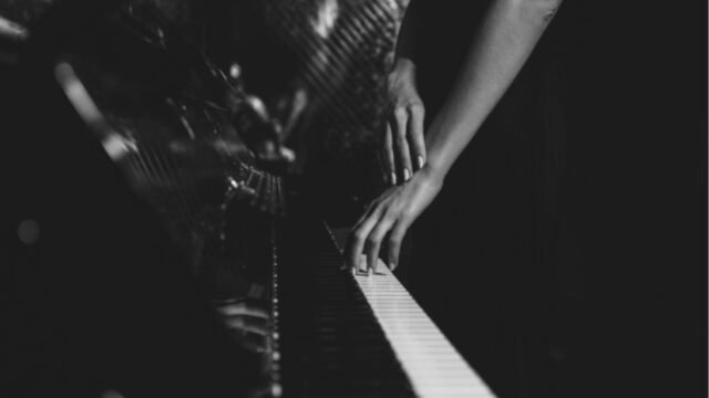 a black and white image a a woman's hands playing the piano