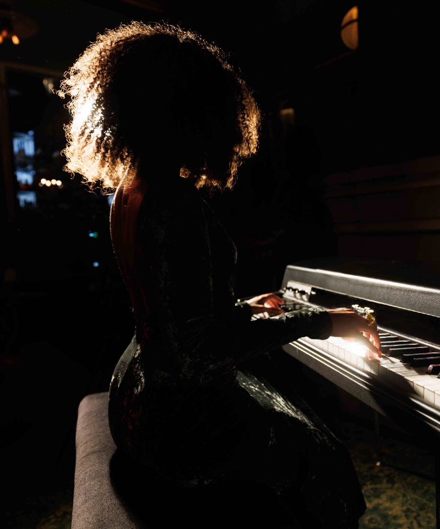Woman sitting at and playing on an electric piano at Club Room.