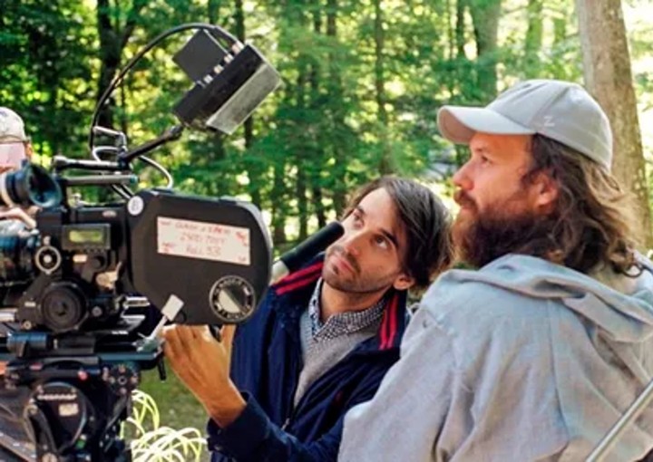 Two men viewing a cinema camera in the woods