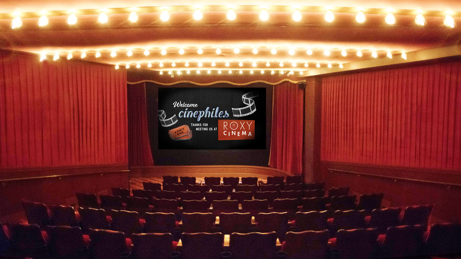 the interior of the roxy cinema new york's screening room with classic red accents. The screen reads "Welcome Cinephiles"