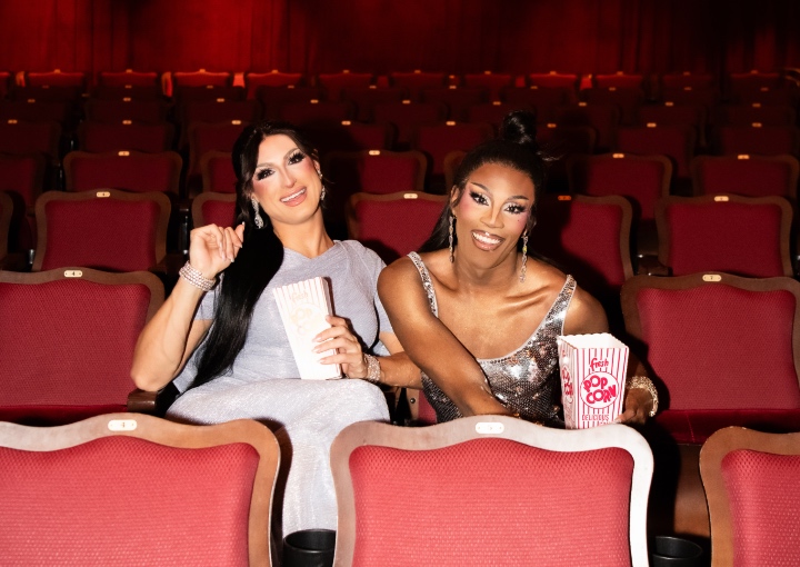 Two Drag Performers posing in the red seats at Roxy Cinema.